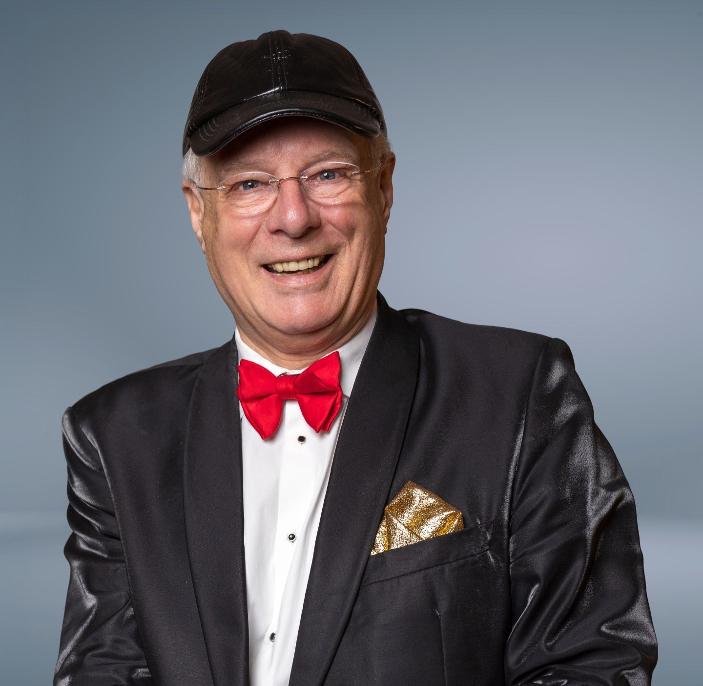 Professor Drabb, handlezer, lachend in smoking met rode strik en zwarte pet